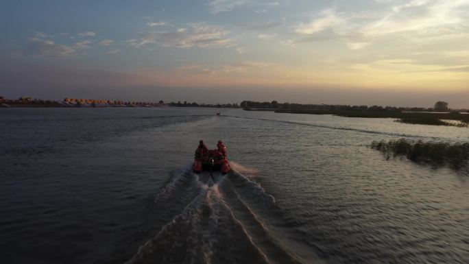 消防员乘坐冲锋舟行驶在夕阳下