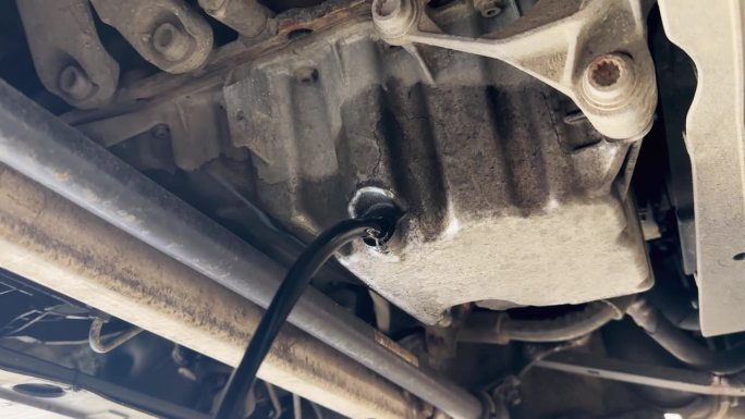 汽车发动机在漏油。机油正从发动机滴到地面上。紧急和需要立即关注汽车发动机的概念