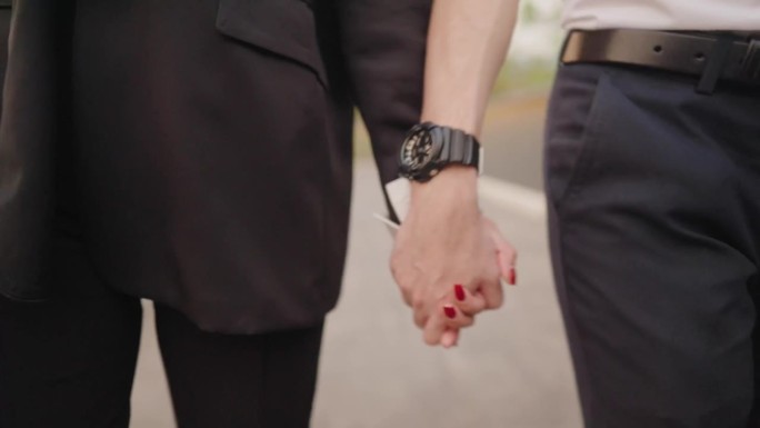 中景特写:两名上班族手牵着手一起回家。