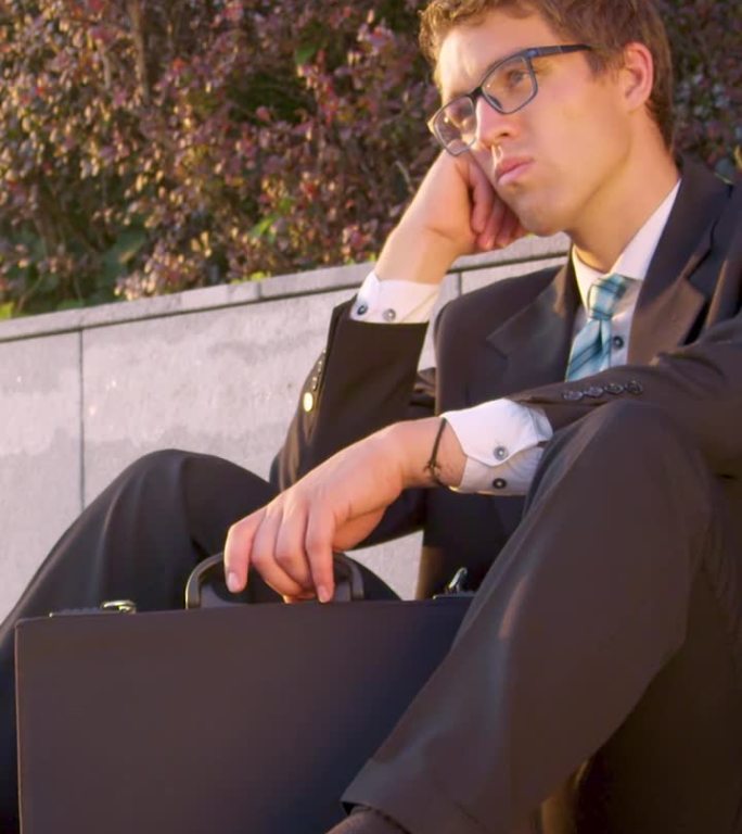 商人失业后坐在人行道上摇头