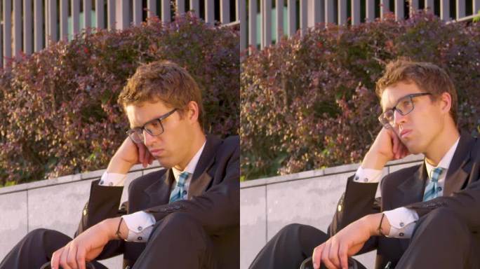 商人失业后坐在人行道上摇头