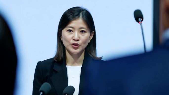 新闻发布会现场的年轻女新闻发言人讲解政策
