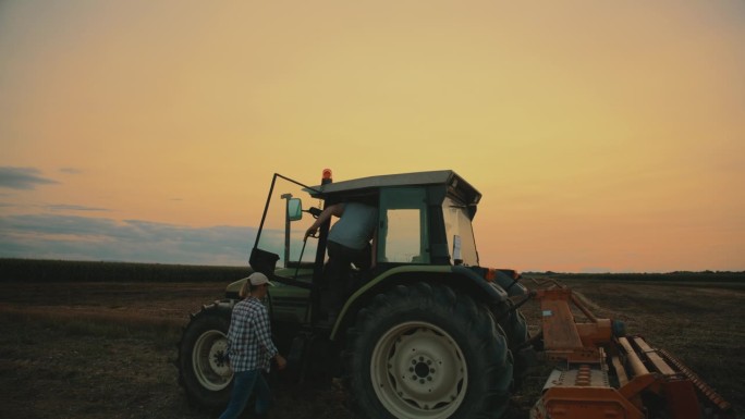 日落时分爬进拖拉机驾驶室的农民:田野里的团队合作时刻