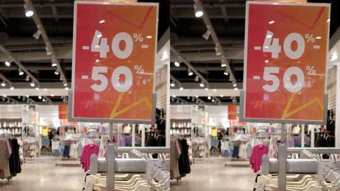 玻璃窗上挂着红色的牌子，上面写着“打折40- 50%”。服装店黑色星期五大减价，五折促销。垂直格式视