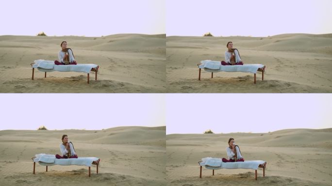 一个女人坐在沙漠中的床上喝着茶