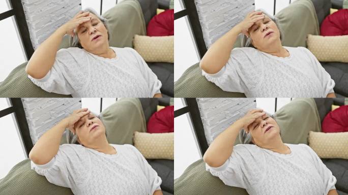 老年妇女感到头痛不适，在家里的沙发上休息，表现出痛苦和不适。