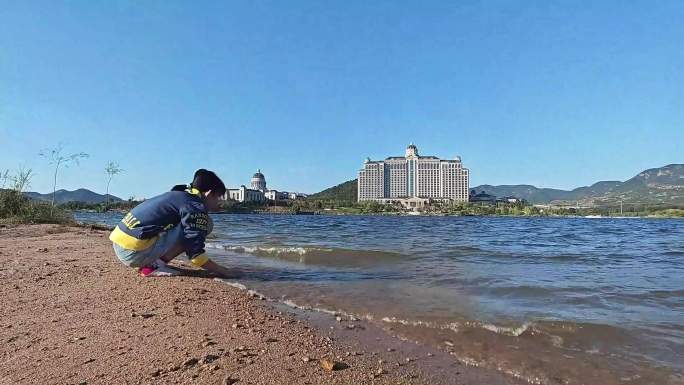 小孩玩水玩沙子，浪打岸