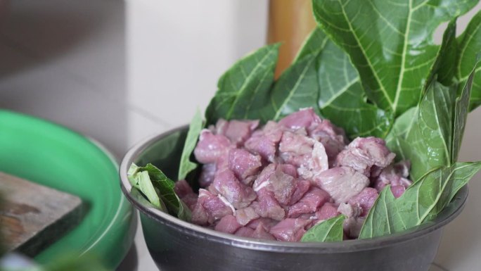 牛肉被放在一个容器里，里面衬着大的木瓜叶