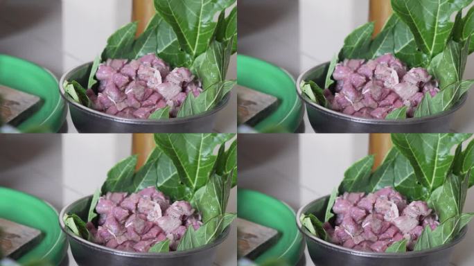 牛肉被放在一个容器里，里面衬着大的木瓜叶