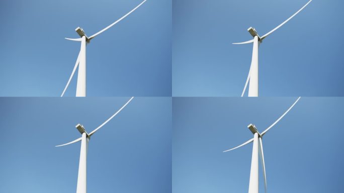 旋转的风力涡轮机。绿色清洁能源未来概念。风车在蓝天上旋转，阳光照耀。用于电力生产的一组风力发电机。风