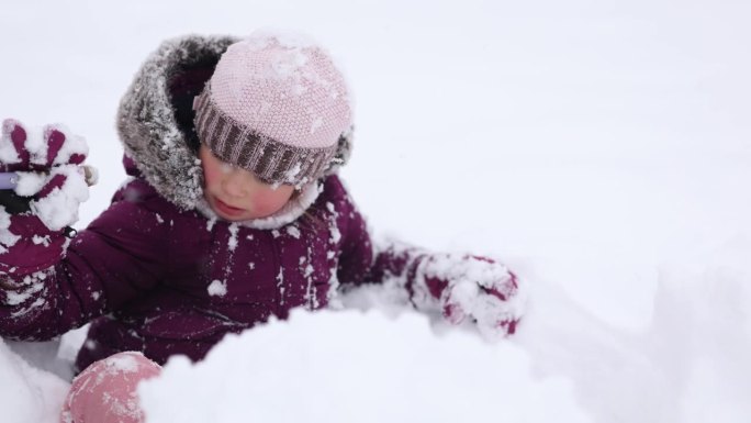 一个穿着冬季衣物的小女孩在深雪中快乐地微笑，捕捉到雪天的魔力。