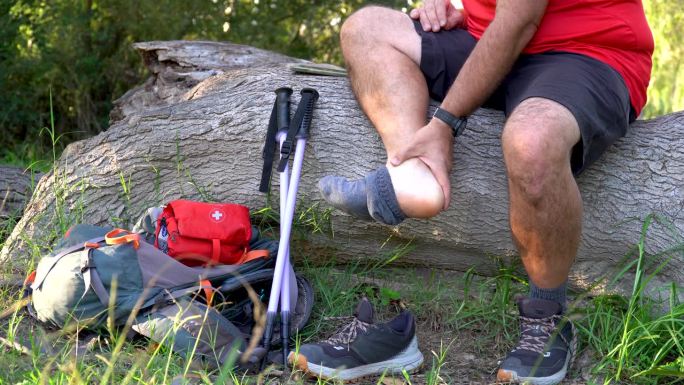 一名徒步旅行者触碰他疼痛的脚踝。