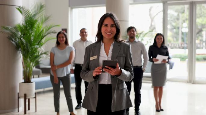 快乐的酒店经理和她的团队都面向镜头微笑。