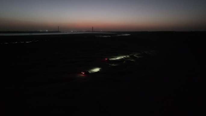 夜幕降临后越野车在漆黑的长江沙洲上行驶