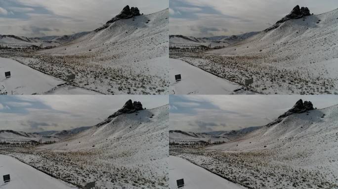 两座高耸的岩石山峰被雪覆盖，俯瞰着平坦的地形，远处是一片延绵的山脉。