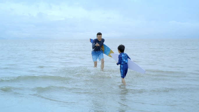 父子跑向大海冲浪戏水开心玩耍度假美好生活