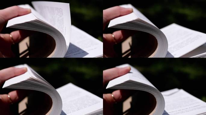 女孩在阳光照射下的自然中翻阅一本打开的书。