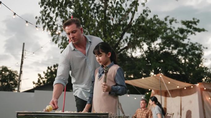 全家一起在花园露营，父亲和女儿在烤食物。分歧。