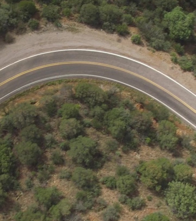 航拍：SUV汽车沿着蜿蜒的山间小路穿过森林行驶。