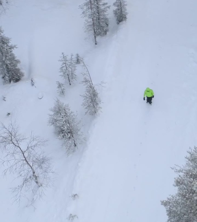 航拍：一个无法辨认的人在神秘森林中的雪-covered道路上行走。