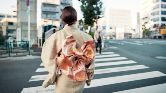 城市，走路的女人穿着和服在斑马线上，背影出现在户外早晨通勤的道路上。文化，时尚，女孩穿着传统日本服装