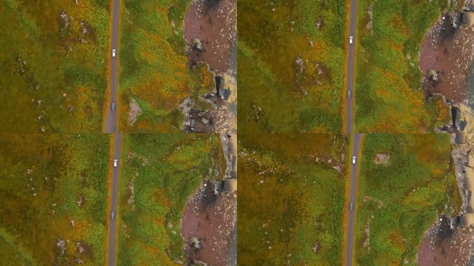 俯视无人机镜头跟随两辆汽车沿着苏格兰高地的C1091公路在苹果十字半岛沿海行驶。