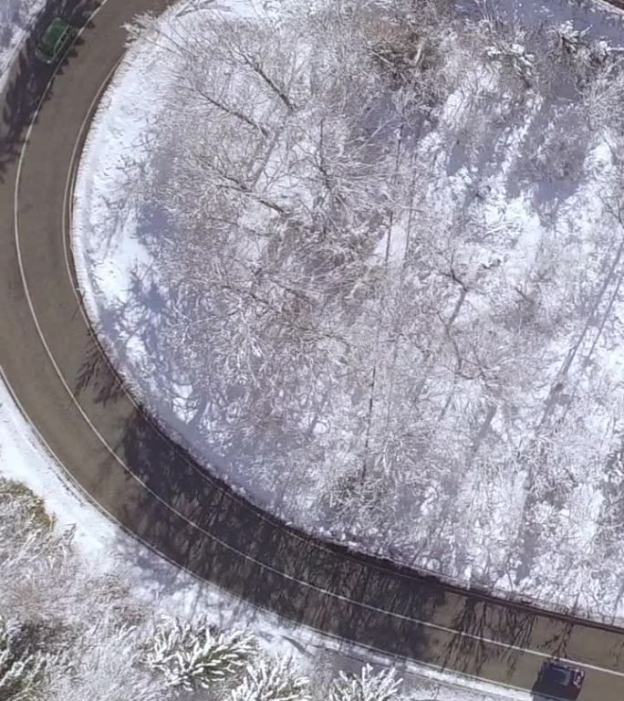 航拍：冬季密林中，汽车在蜿蜒的乡村道路上飞驰。