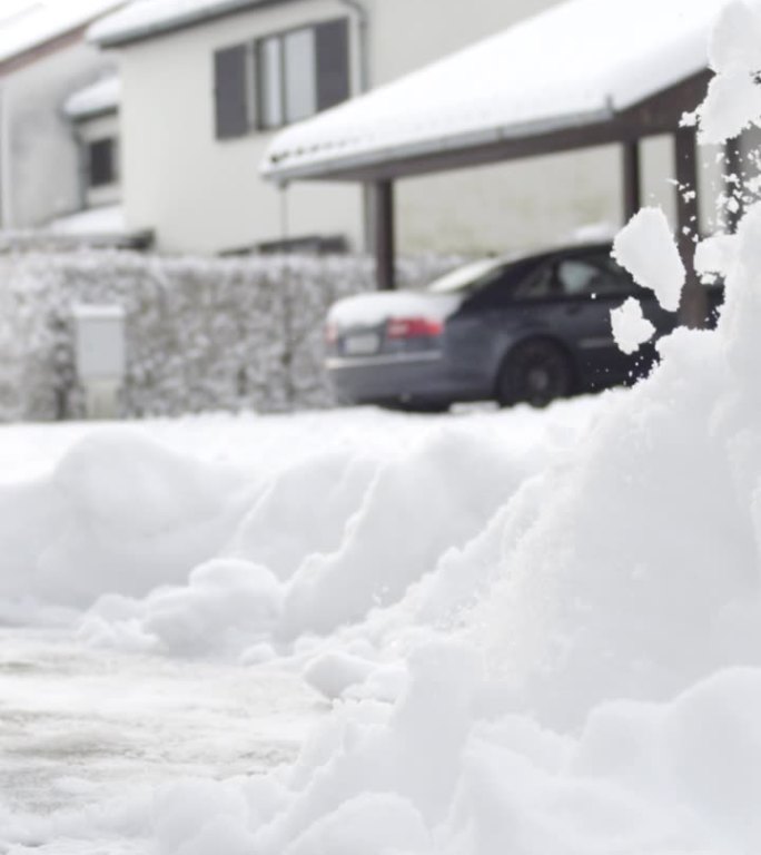 特写：男子在理想的郊区小镇前清理新雪。