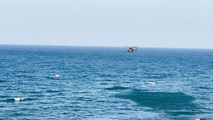 救援直升机在湛蓝的晴空中低飞，正在海面上方进行巡逻。