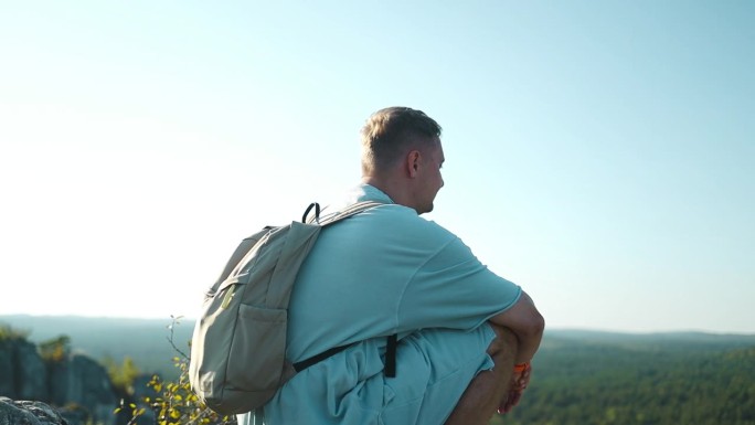 白人金发男旅行者坐在悬崖桥边，俯瞰森林的鸟瞰图。旅行生活方式冒险假期概念。