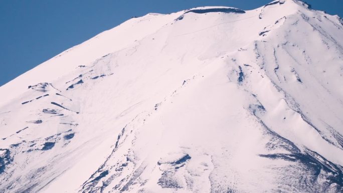 在晴朗无云的天空下，长焦镜头捕捉到富士山的雄伟壮丽的雪覆盖山峰，这是一处著名的日本地标，拍摄于日本山