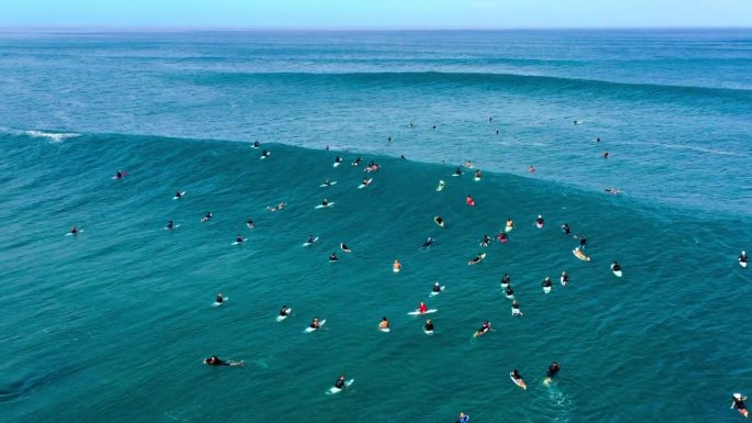 度假时人们拿着冲浪板在波涛汹涌的大海中游泳的航拍倒拍——夏威夷的威基基