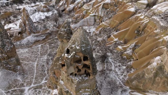 土耳其卡帕多西亚国家公园雪景中火山岩上历史悠久的洞穴房屋的航拍镜头