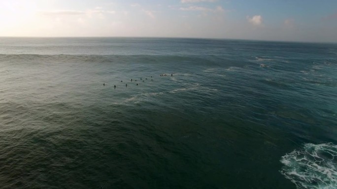 人们在海浪上冲浪的空中封锁镜头，在日落时无人机飞行-夏威夷瓦胡岛