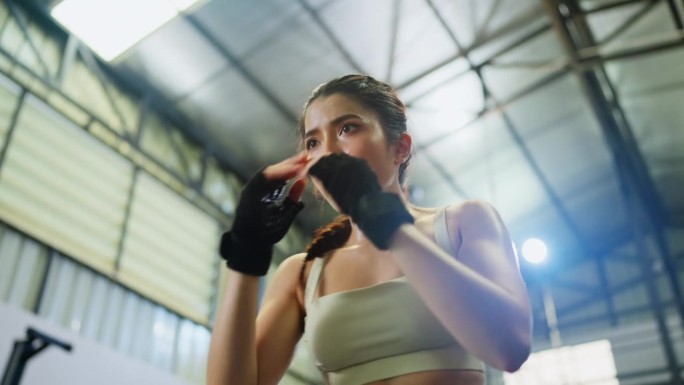 美丽的亚洲运动女性在体育馆里练习太极拳，她看起来很专注，为了身体健康而练习。