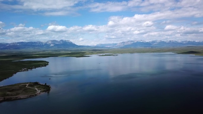 空中拍摄的湖与船在山脉附近的天空，无人机在自然景观上向后飞行-比林斯，蒙大拿