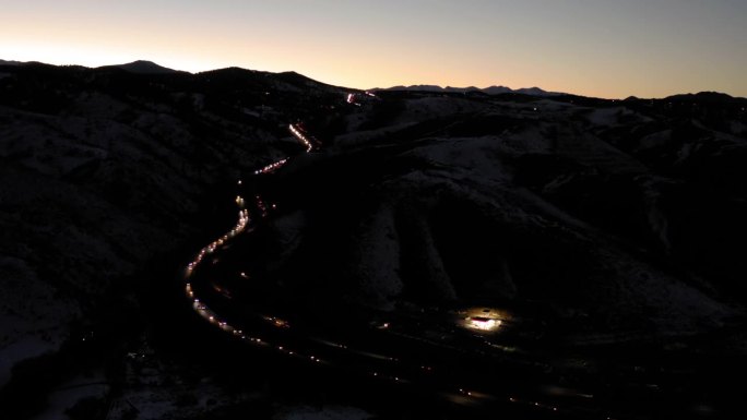 空中拍摄的车辆移动在黄昏在山麓的高速公路上，无人机在景观上平移-丹佛，科罗拉多州