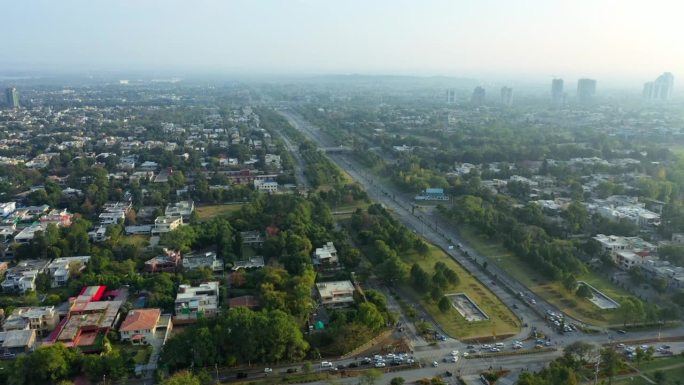 在一个朦胧的早晨，高速公路和广阔的城市上空的空中调幅，远处高楼耸立——巴基斯坦伊斯兰堡