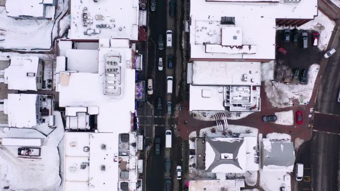 空中减速上升直接在被雪覆盖的城市建筑物、屋顶和交通-公园城，犹他州