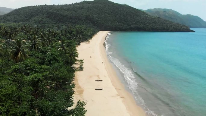 空中向后:在郁郁葱葱的丛林中风景优美的热带海滩上的船只