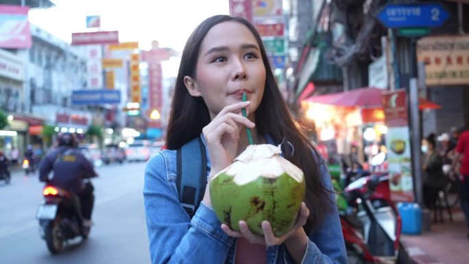 亚洲游客喝着椰子汁，摇瓦叻，摇瓦叻，在曼谷市中心的热门景点