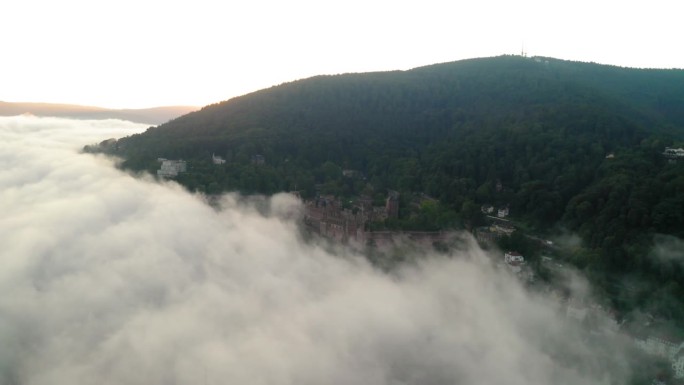 在阿尔卑斯山上的著名宫殿的空中美景，日出期间无人机在云上向前飞行-海德堡，德国