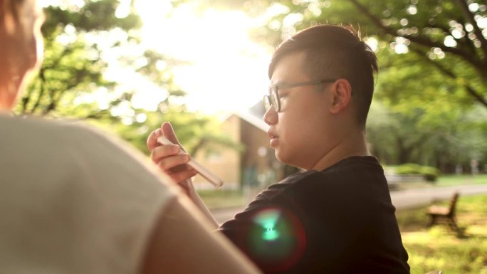 一名亚洲男子和一名白人女子在公园里使用带有语音识别功能的语言翻译功能交谈。