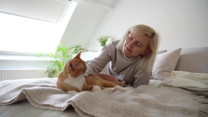 一位年轻女子躺在床上抚摸着她的红斑猫