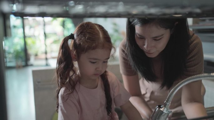 妇女和女孩打扫房子。女孩在打扫和洗盘子。