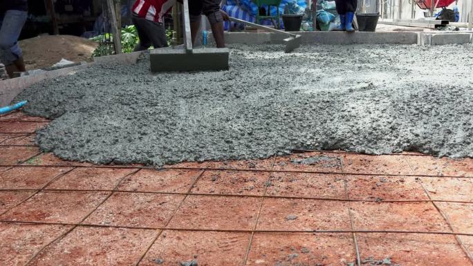 许多建筑工人帮忙平稳地浇筑水泥和抹灰。