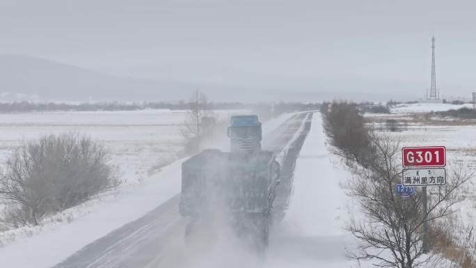 物流运输汽车行驶在冬季飘雪的公路上