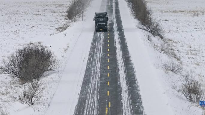 物流运输汽车行驶在冬季飘雪的公路上