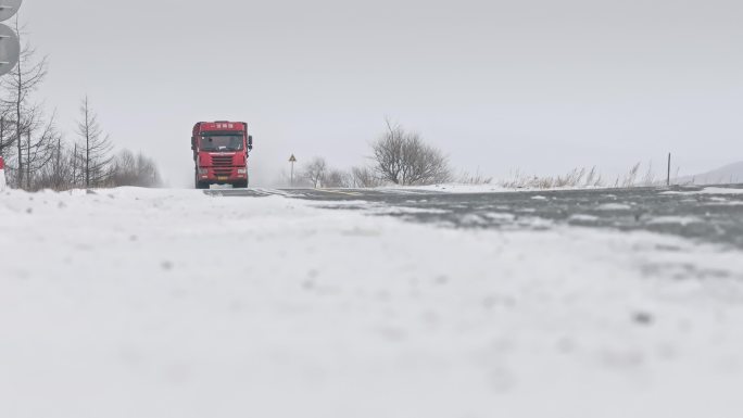 物流运输汽车行驶在冬季飘雪的公路上