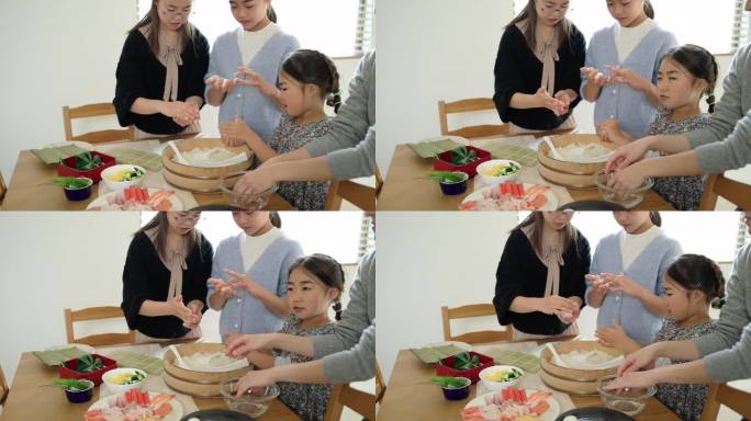 三个日本女孩和她们的母亲正在卷醋饭做寿司。